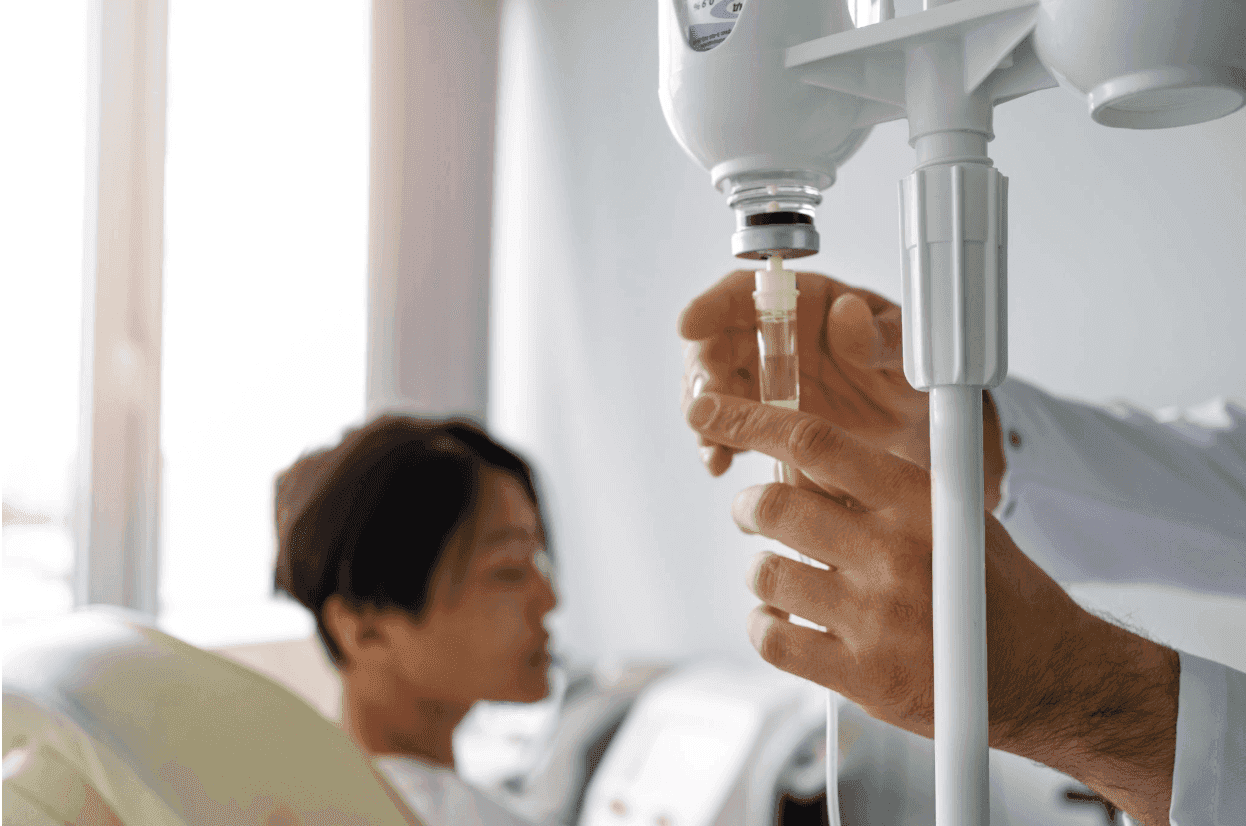 A doctor's hands adjusting an IV drip for a patient in a medical office.