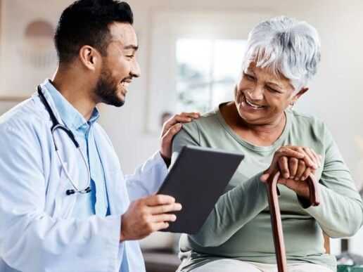 Doctor talking to smiling elderly lady with a cane