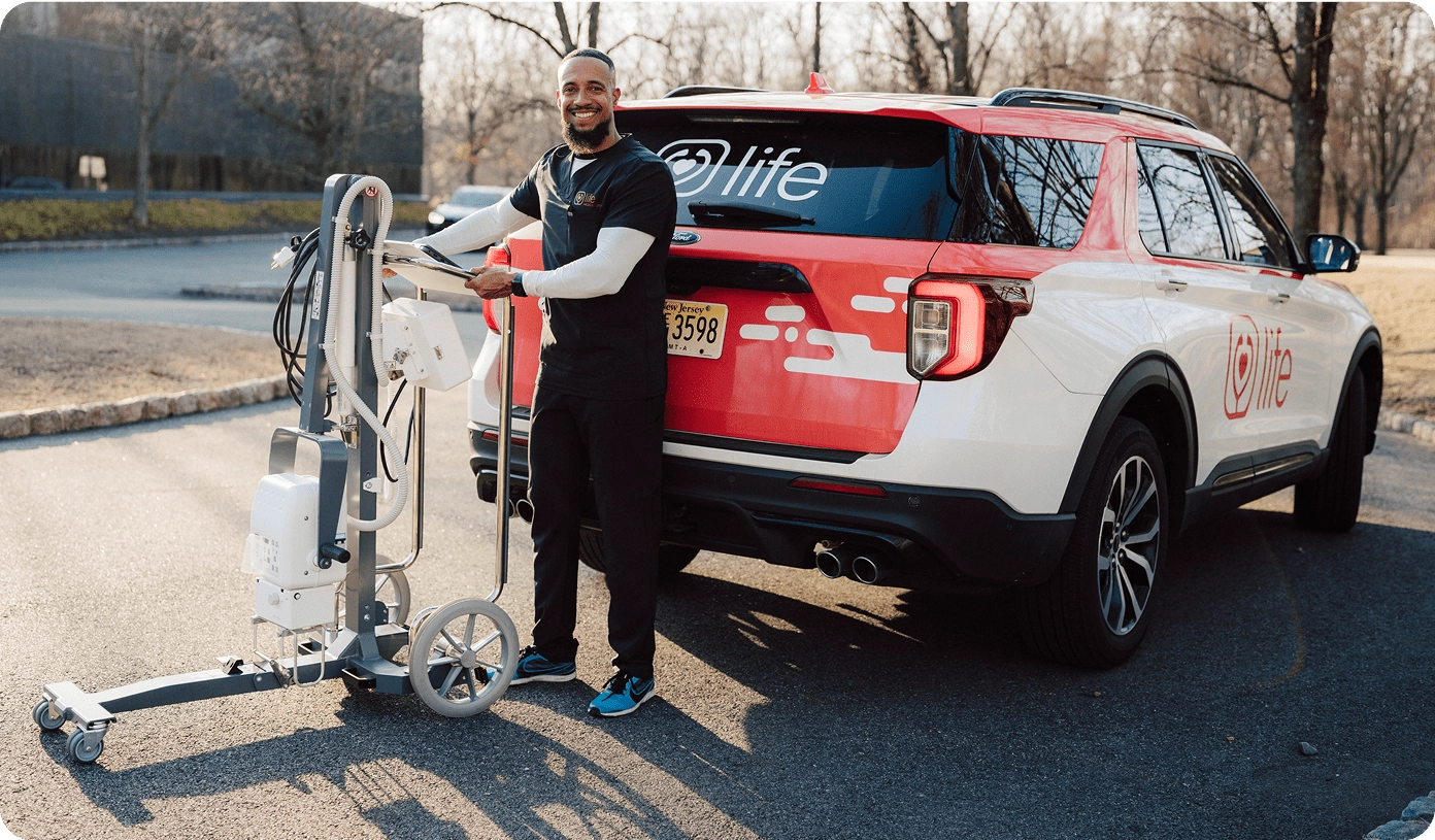 Mobile medical worker with portable diagnostic equipment next to a Life branded vehicle.