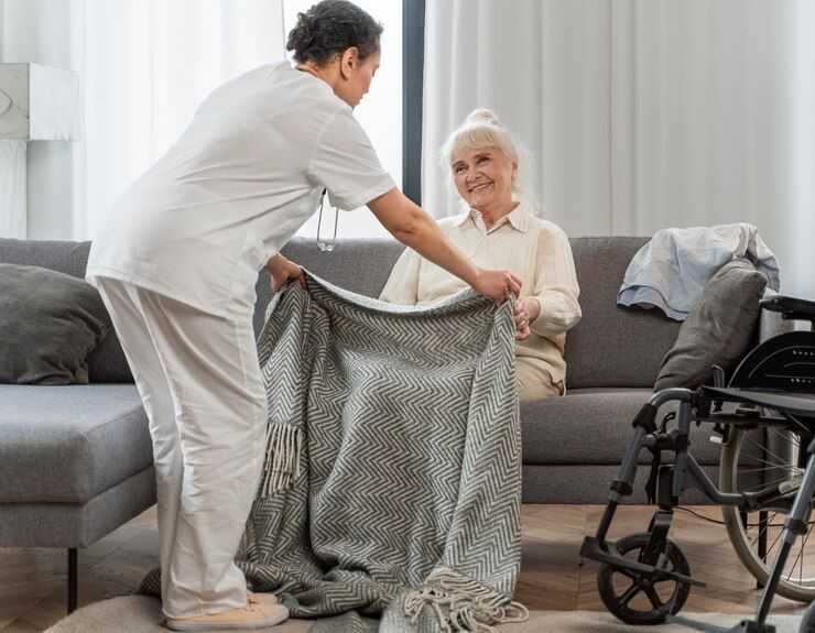 nurse putting blanket over senior woman on couch