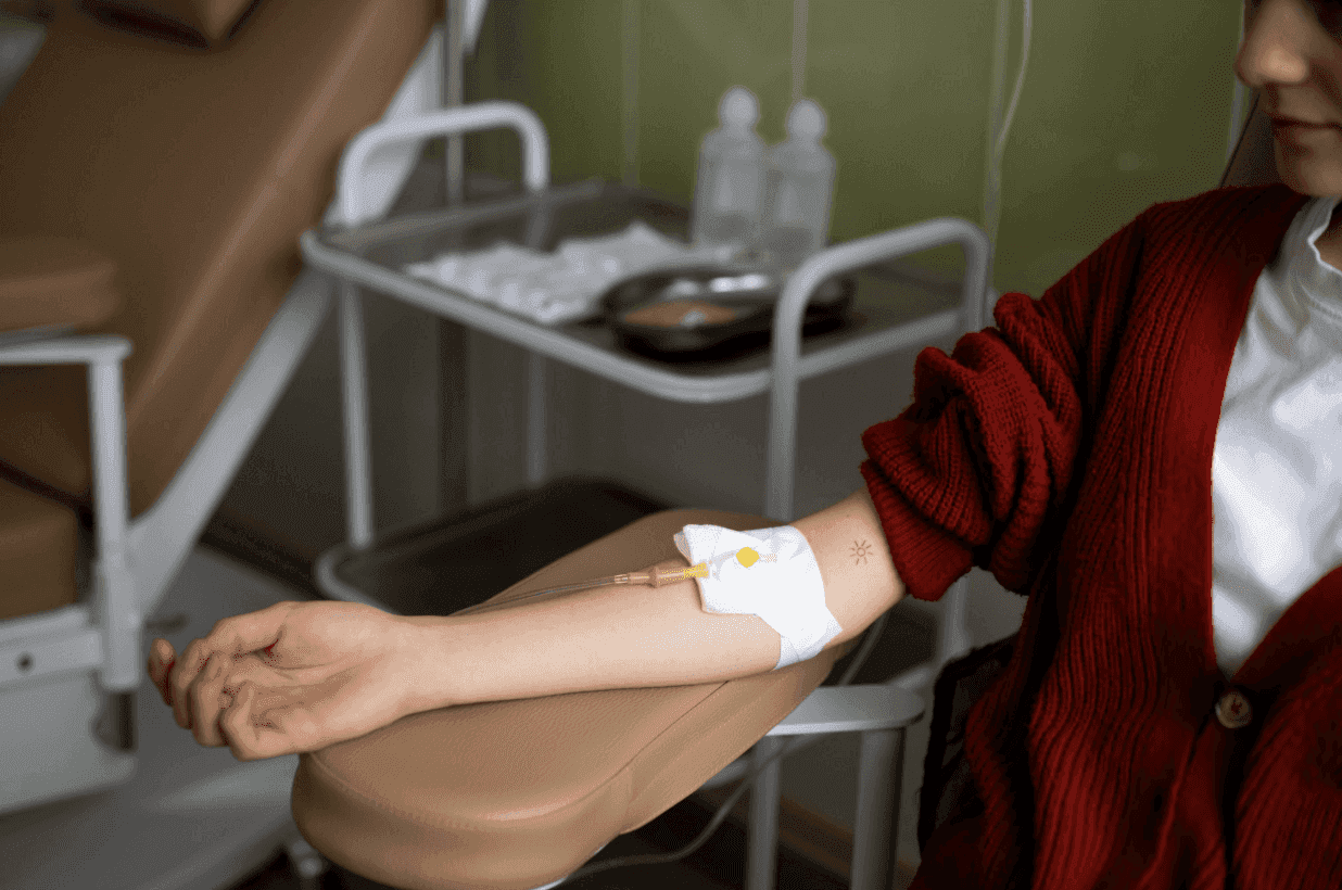 A patient in a red sweater receiving intravenous (IV) treatment.