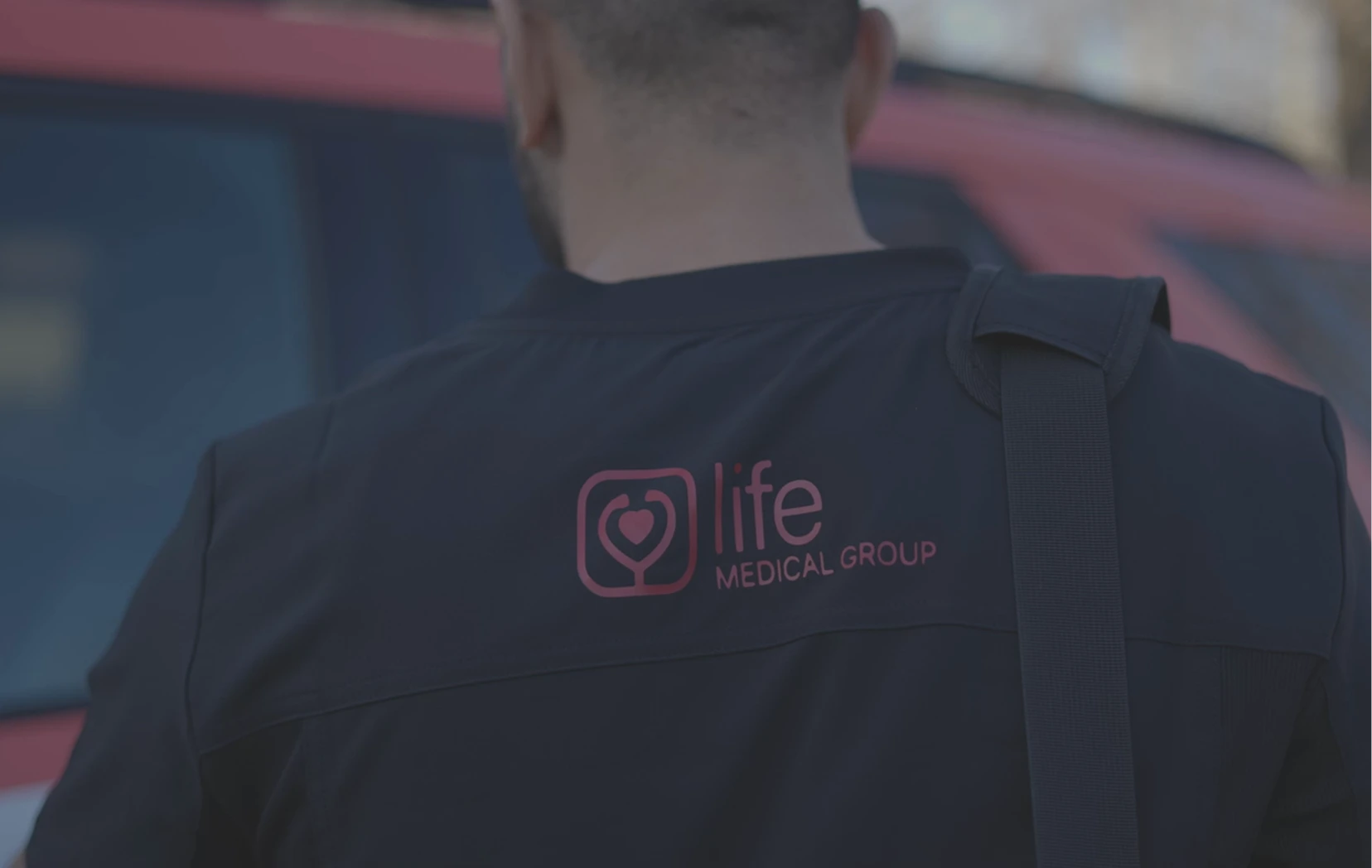 Smiling MobileCare healthcare professional in uniform standing in front of company logo at medical office.
