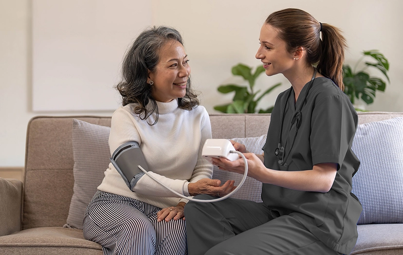 Nurse providing at-home chronic care support, helping a senior patient manage their health.