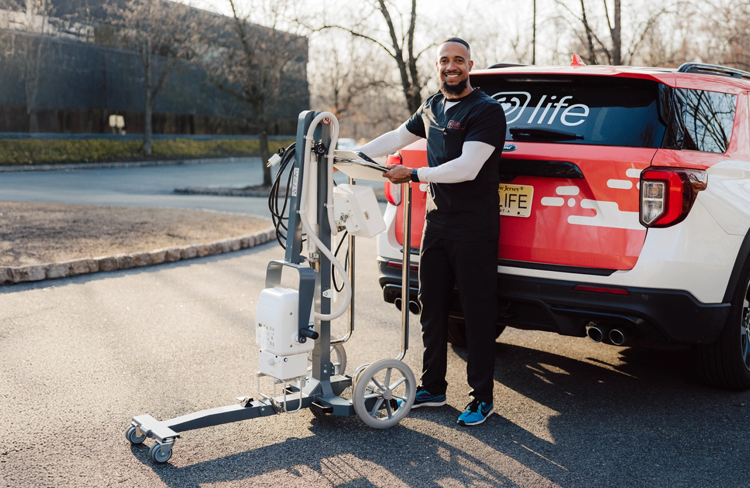 MobileCare technician with portable X-ray machine standing next to branded vehicle, providing in-home imaging services.