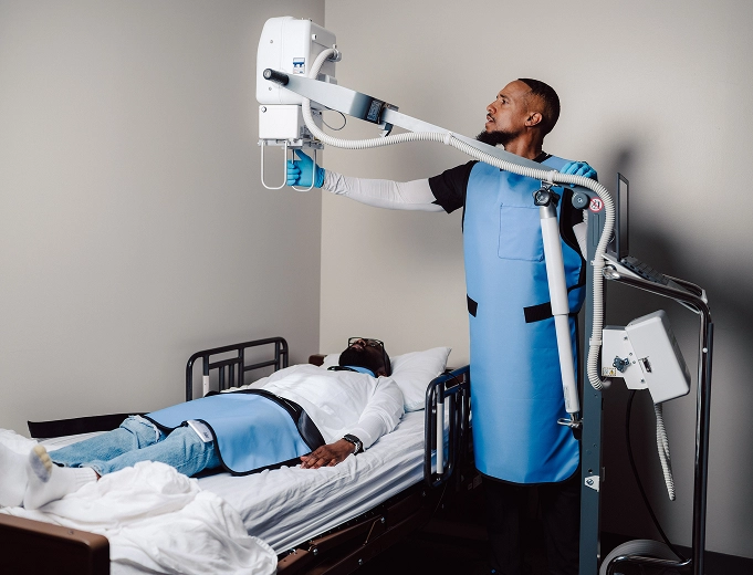 MobileCare technician performing an in-home X-ray for a patient lying in bed using portable imaging equipment